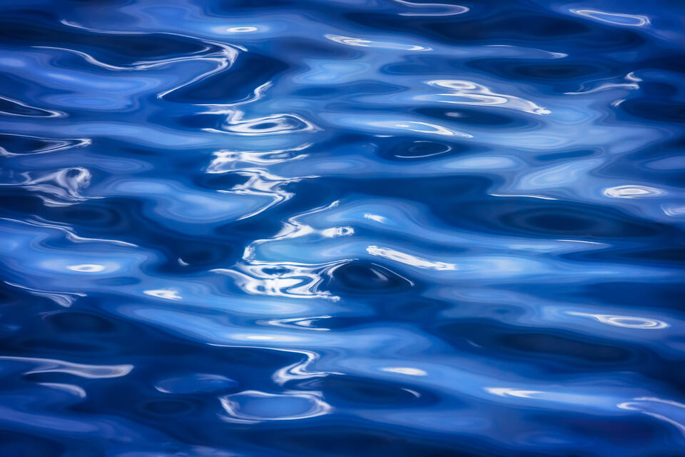 White clouds and a blue summer sky reflect in the surface of a lake in New York's Adirondack Mountains.