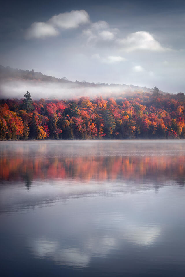 Morning mist gives a dreamy feeling to a mountainside covered in beautiful fall foliage in the Adirondacks of New York.