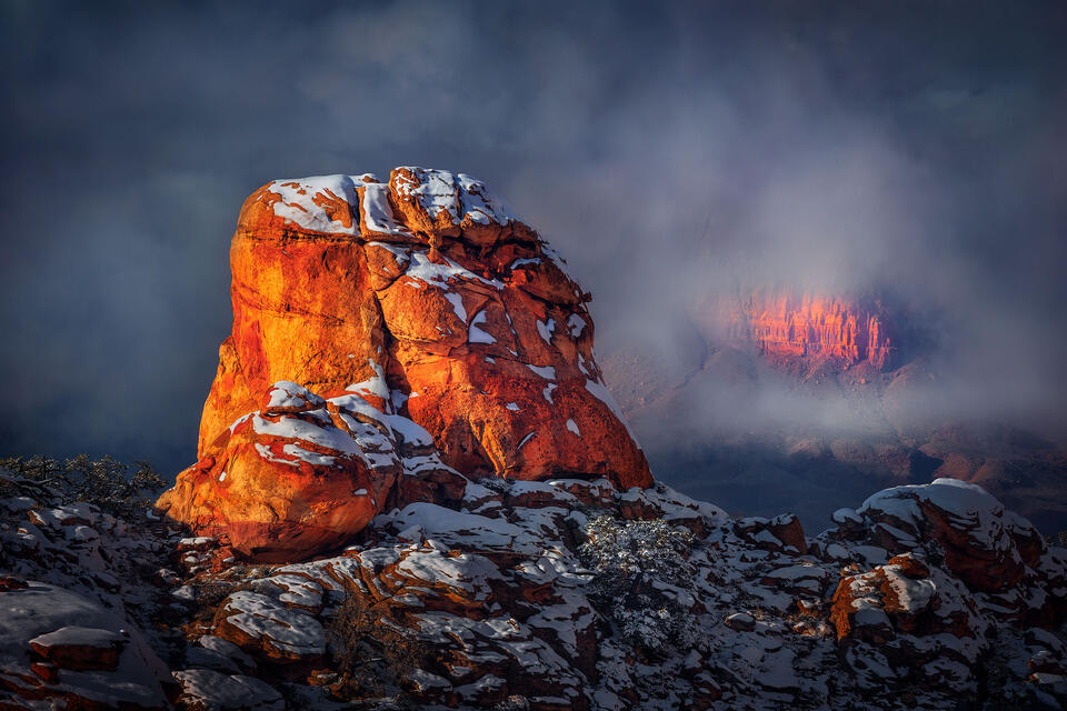 A snowcapped hoodoo gazes out to a sliver of canyon in the distance.