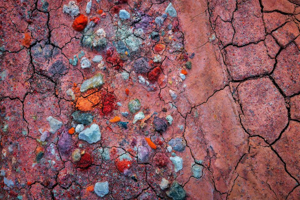 Colorful stones washed down from bentonite badlands after a heavy rain became trapped in the cracked earth once it dried.