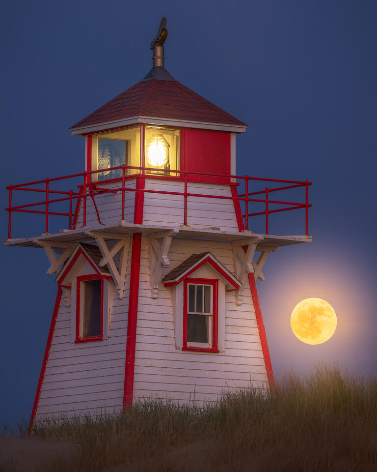The bright full moon is visible behind Covehead Harbo Lighthouse.