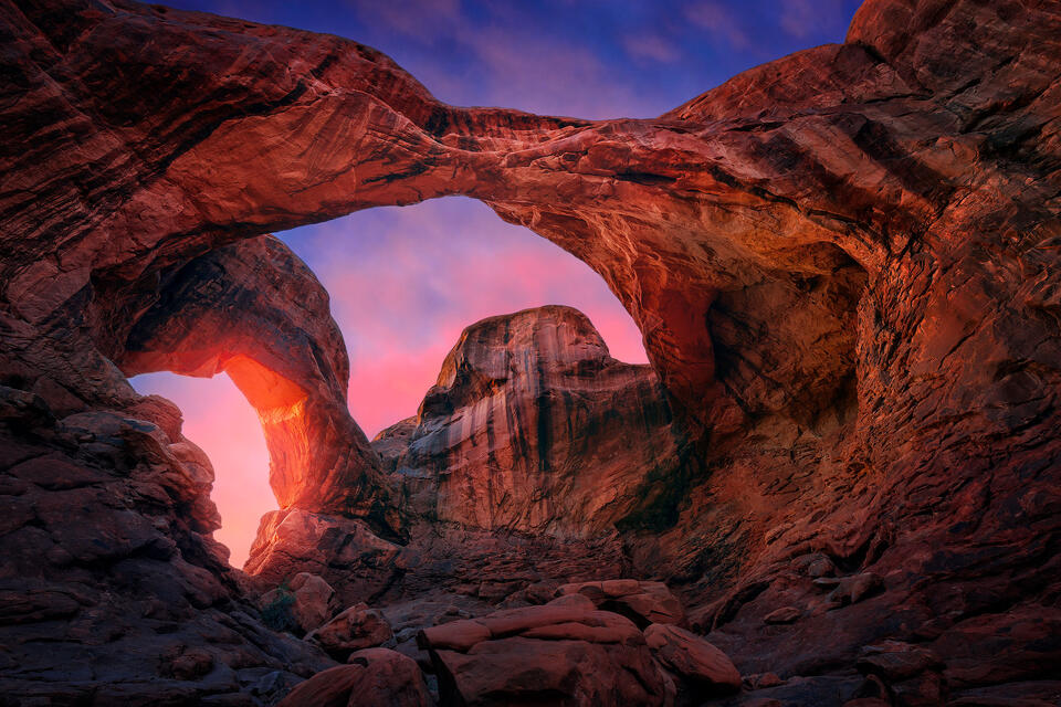 A colorful sunset lights up the twin spans of Double Arch in Utah’s Arches National Park.