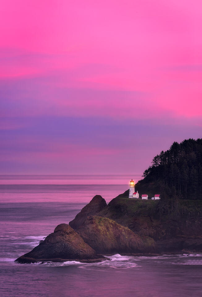 A pastel sunrise illuminates the sky and ocean surrounding Heceta Head Lighthouse.