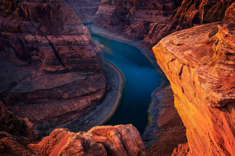 The Colorado River winding its way through the shadows of the canyon in Horseshoe Bend at sunset.