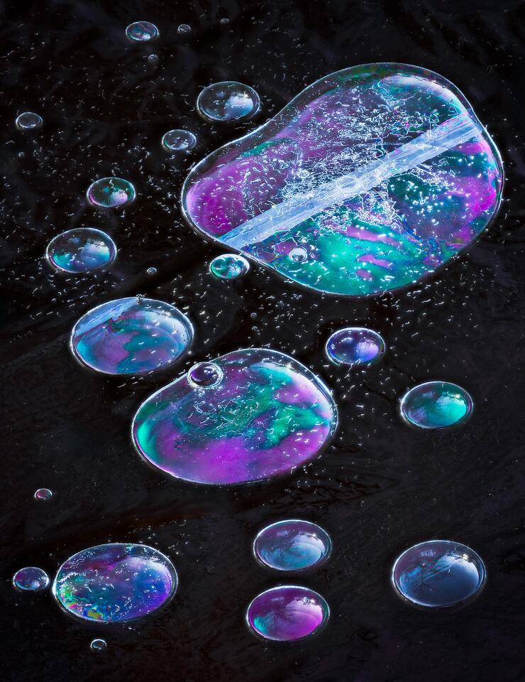 Multicolored bubbles are trapped under a frozen pond.