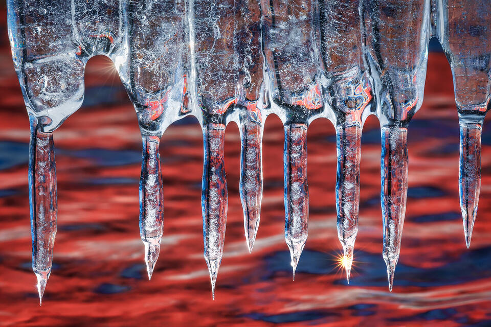 Abstract composition of icicles hanging down from the underside of a boat dock, where they glowed with the low-angled winter sunlight.
