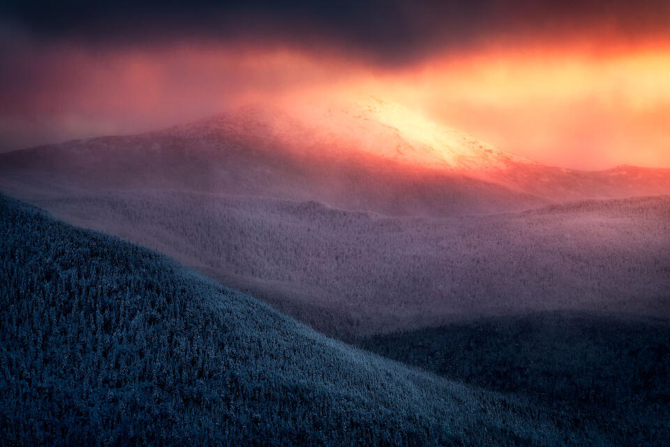 Mount Marcy pokes through clouds during a winter sunset. 