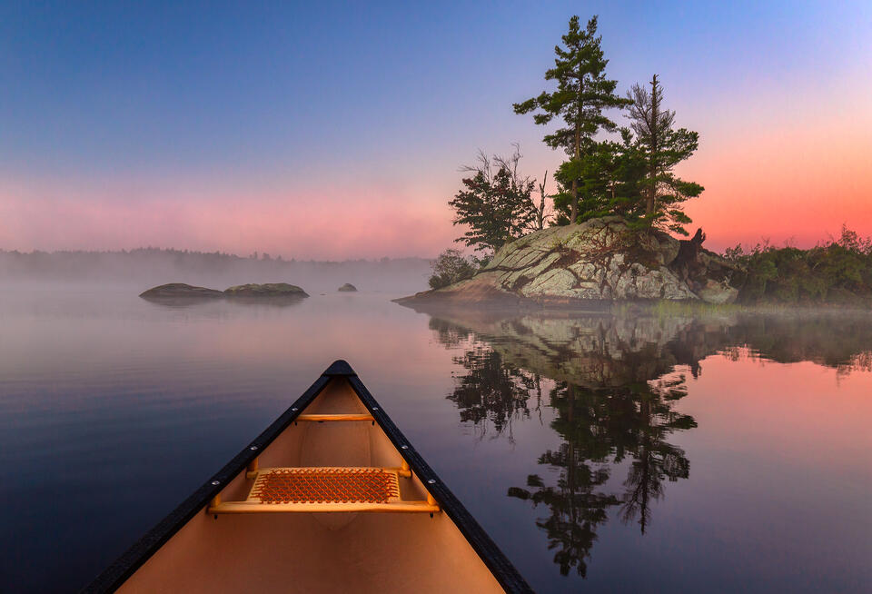 An island reflects perfectly in water during a morning sunrise paddle.