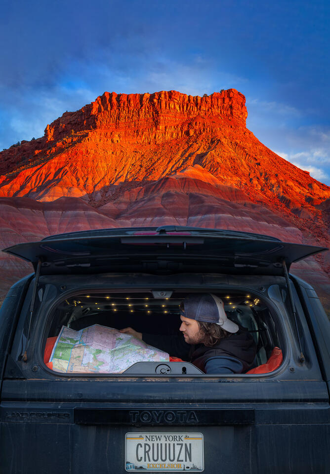 Looking at a map in the back of a Land Cruiser with the Paria Badlands in the background