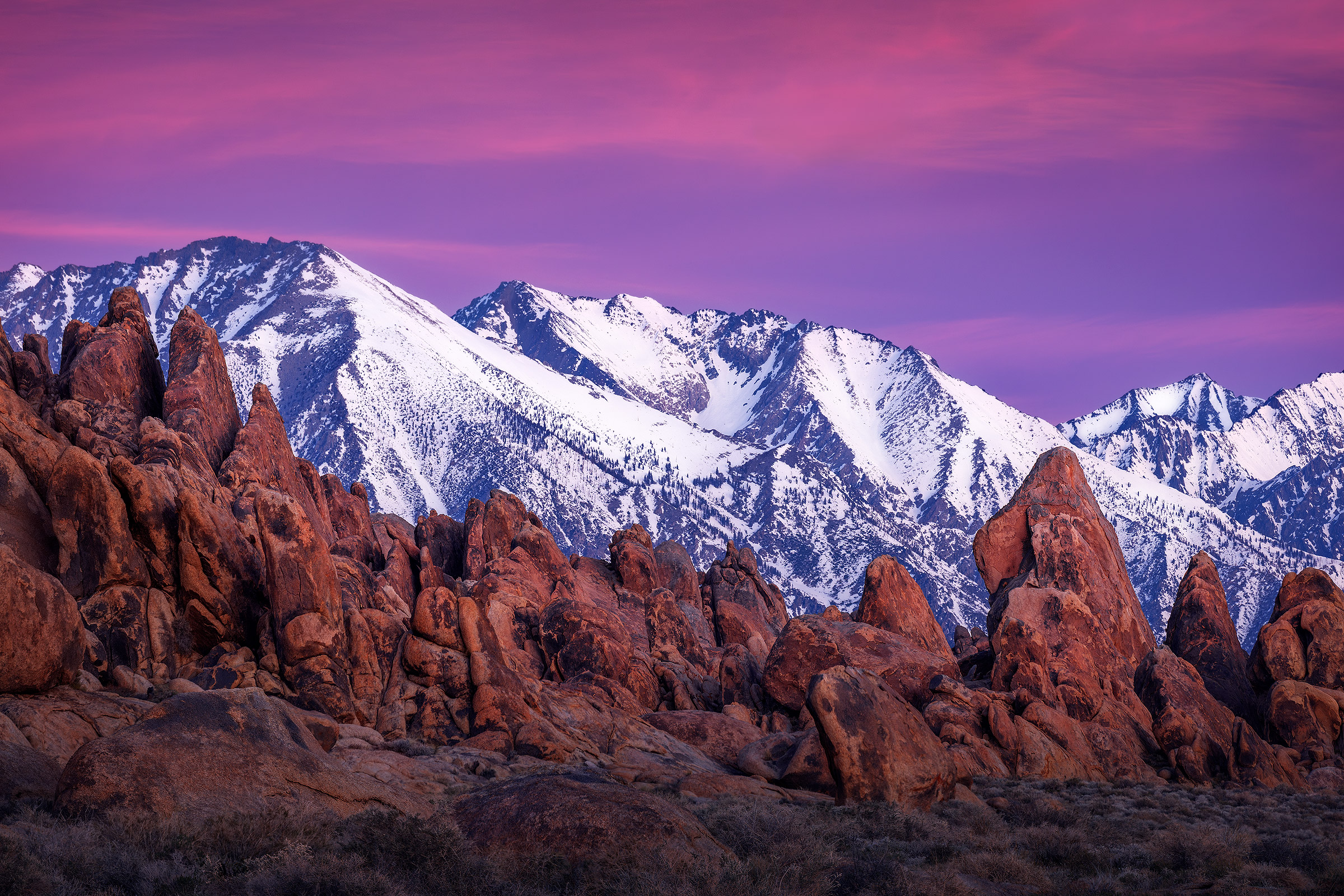 Soft Sierra Sunrise A warm pre-sunrise glow lights up the sky above the snowy mountains and unique boulders of California's Alabama Hills.