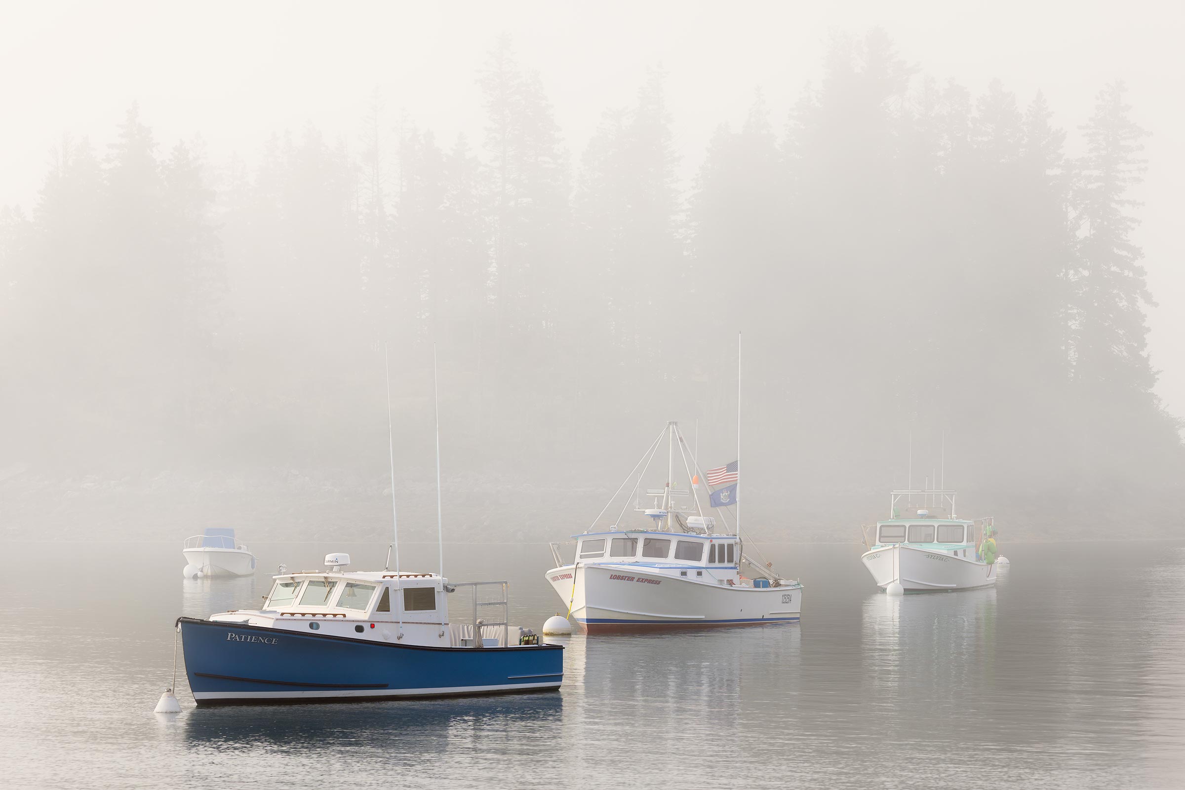 Slowly Vanish A group of lobster boats stand out from the thick morning fog on a summer morning in Port Clyde, Maine.